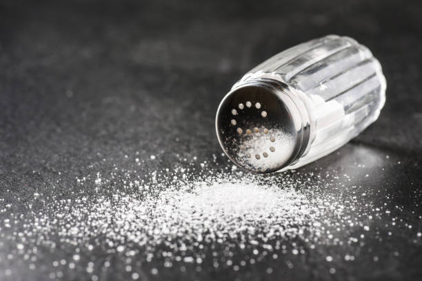 istock Salt. Glass salt shaker on dark stone table. 1214887508