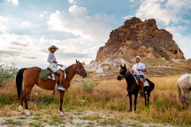 Photo of Cappadocia Turkey during sunrise, couple mid age men and woman on vacation in the hills of Goreme Capadocia Turkey, men and woman looking sunrsise with hot air balloons in Cappadocia