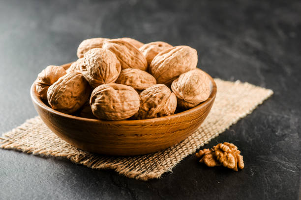 Walnuts in wooden bowl. Whole walnuts in vintage bowl on jute.