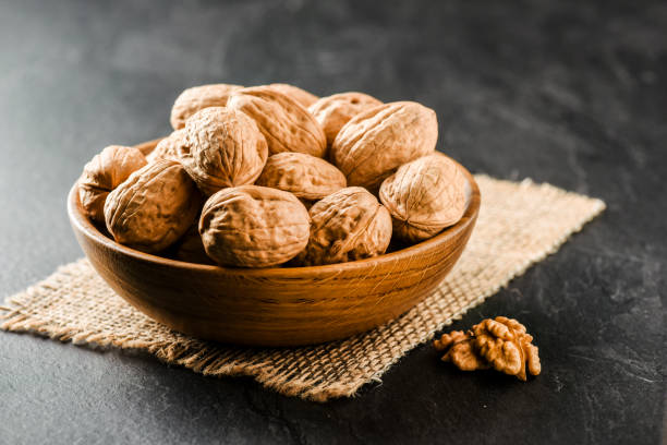 Walnuts in wooden bowl. Whole walnuts in vintage bowl on jute. stock photo