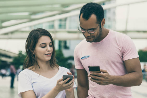 istock Front view of two young people walking with smartphones 1214887934