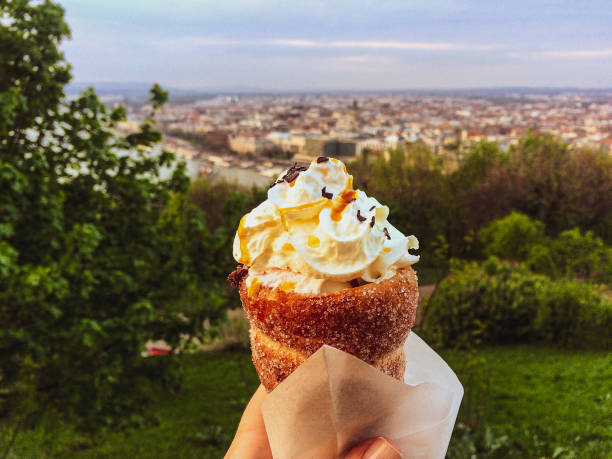 trdelnik with ice cream on a background of Budapest spit roll with sugar and cinnamon with ice cream on a Buda hill overlooking Budapest trdelník stock pictures, royalty-free photos & images