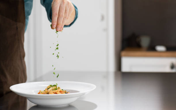 Nothing Goes To The Table Before It's Perfect Cropped shot of a young male chef garnishing food in a professional kitchen. final round stock pictures, royalty-free photos & images