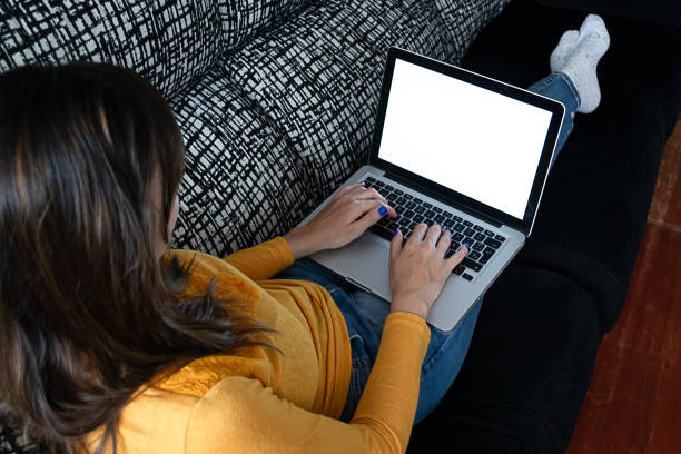 istock Girl using a laptop with a blank screen, lying on the couch. Perfect image for mockup 1214892760