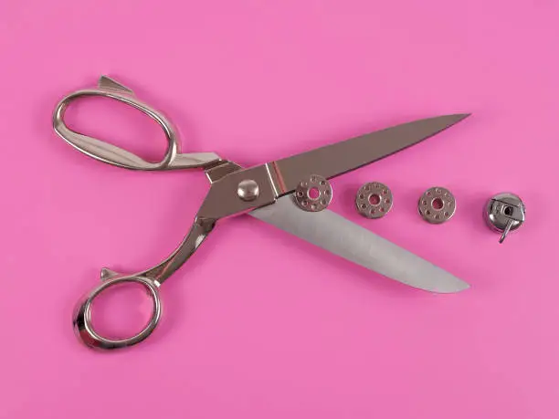 Accessories for sewing thread scissors needle and centimetre on a pink background