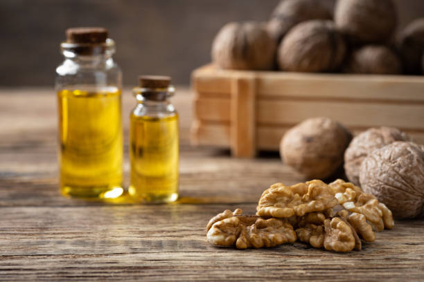 istock Glass bottle with walnut oil and walnut kernel on a wooden table. 1214893348
