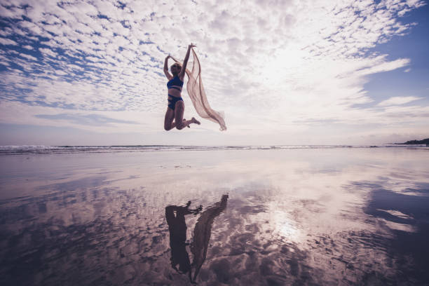 istock Handsome female jumping whit scarf on the beach. 1214894916