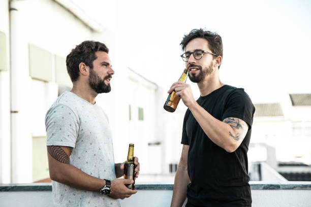 istock Two male friends enjoying party, chatting, drinking beer 1214896074