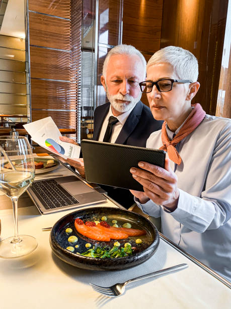 istock Two senior company reps managing finances together while having lunch in an upscale restaurant 1214896292