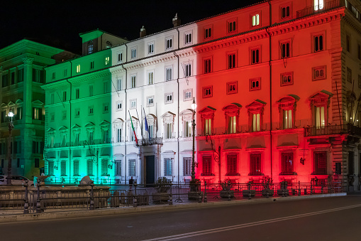 Rome, Italy - March 24, 2020: Palazzo Chigi, seat of the Italian government, facade of the building illuminated with the colors of the Italian flag. Coronavirus emergency Italy.