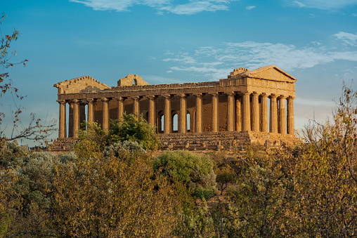 Concordia temple with beautiful sky and statue of angel in front in the Valley of the Temples, Agrigento, Sicily island, Italy