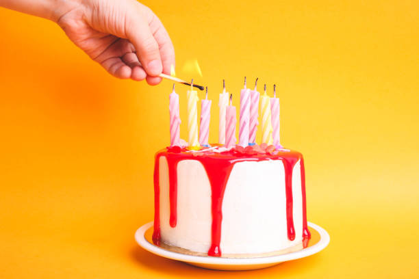 istock Children's hand lights candles on a white cake with red icing 1214901201