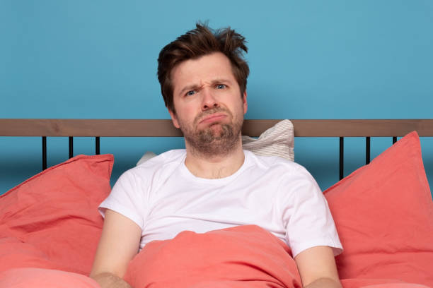 istock Stressed handsome young man sitting in the bed alone feeling unhappy and tired. 1214901576