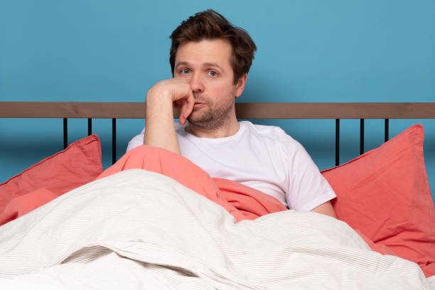 istock Stressed handsome young man sitting in the bed alone feeling unhappy and tired. 1214901604