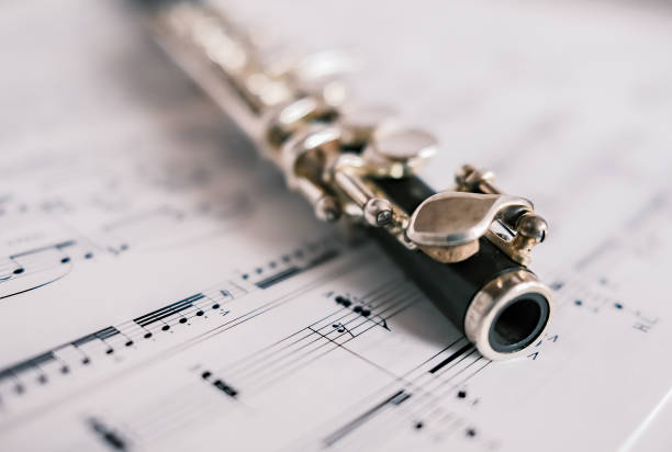 Close up and selective focus of a wooden flute on unidentifiable sheet music Close up and selective focus on a classic wooden flute on a background of unidentifiable sheet music piccolo stock pictures, royalty-free photos & images