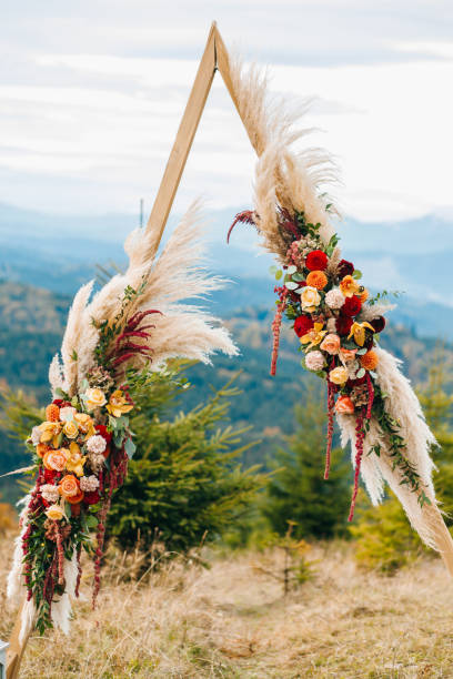 istock Triangular wooden arch with composition of pampasian grass, dahlia and roses. Decorative floristry 1214904212