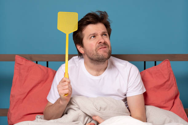 man holding a fly swatter wanting to kill annoying mosquito