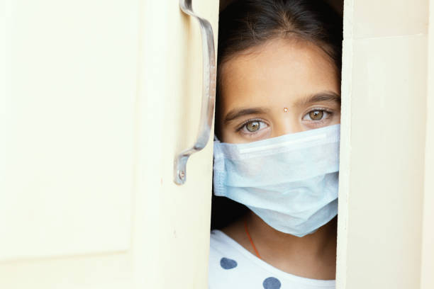 joven triste con máscara médica que se escapa por la puerta de la casa - concepto de cuarentena en casa debido a covid-19 o brote de coronavirus. - isolated despair hope assistance fotografías e imágenes de stock