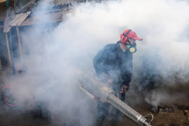 Volunteer with a gas mask was fogging the urban city to prevent the dengue fever.