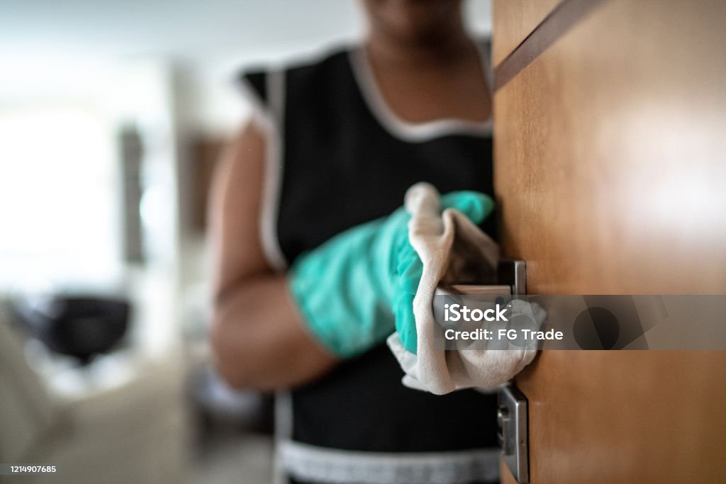 Hands with glove wiping doorknob Cleaning Stock Photo