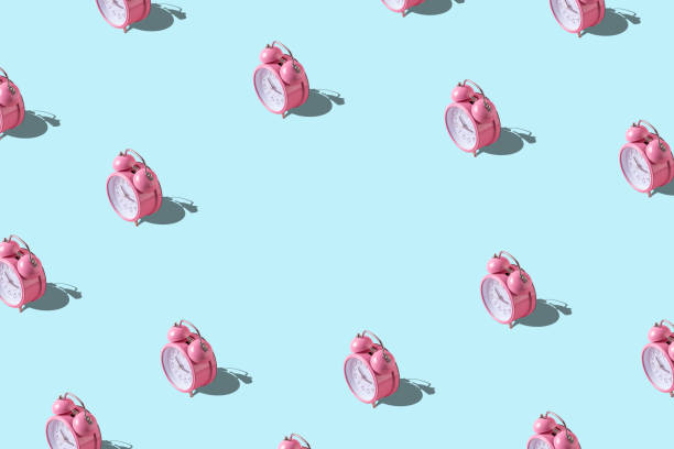 istock Creative pattern with pink alarm clock on blue background. Minimal summer concept. 1214909173