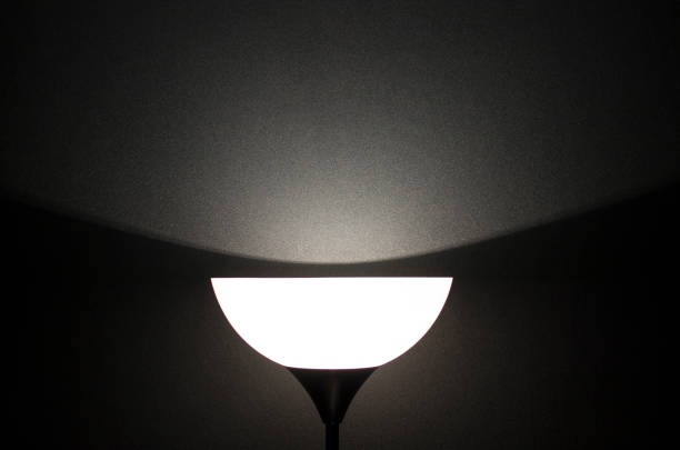 istock A semicircular lampshade illuminates a black rough wall. Background with light and shadow for text. 1214909715