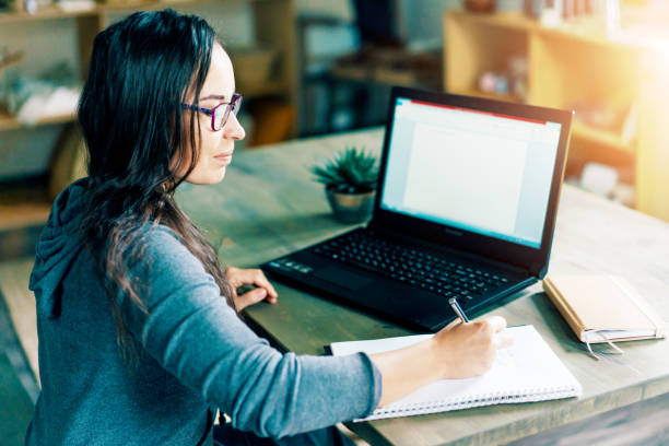 istock woman writes in a notebook near the laptop 1214912399