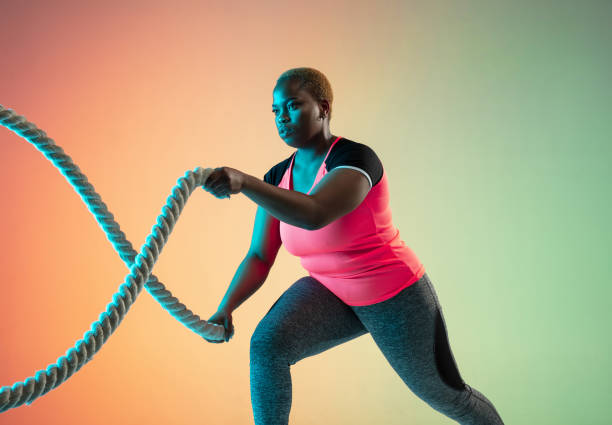 istock Young african-american plus size female model's training on gradient background 1214913723