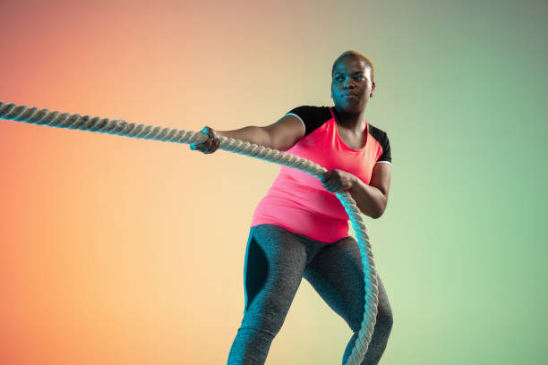istock Young african-american plus size female model's training on gradient background 1214913733