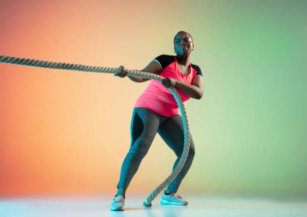 istock Young african-american plus size female model's training on gradient background 1214913734
