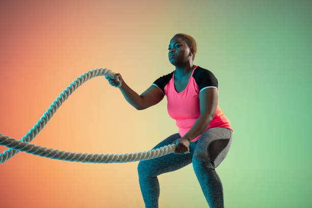istock Young african-american plus size female model's training on gradient background 1214913735