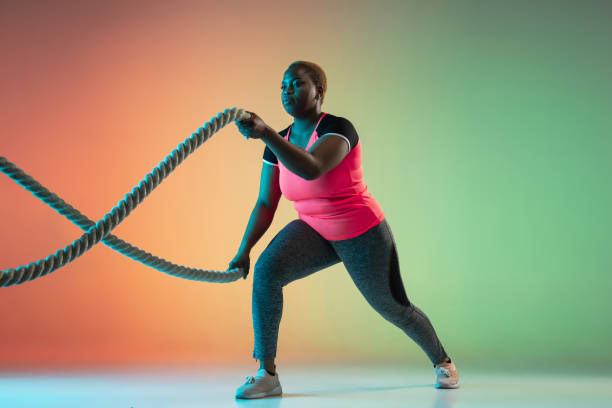 istock Young african-american plus size female model's training on gradient background 1214913744
