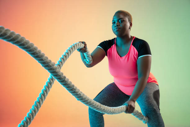 istock Young african-american plus size female model's training on gradient background 1214913750