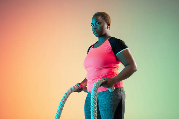 istock Young african-american plus size female model's training on gradient background 1214913753