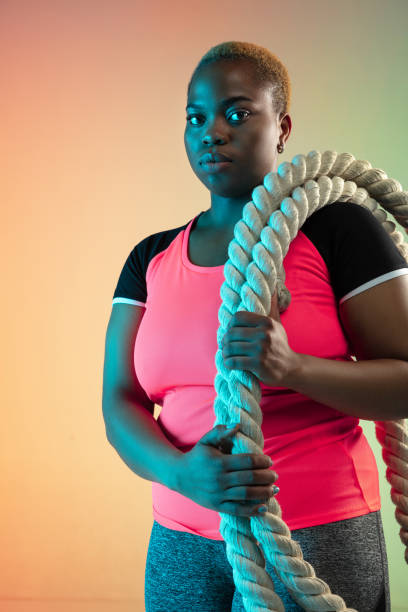 istock Young african-american plus size female model's training on gradient background 1214913770