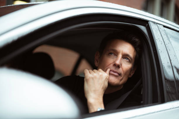 On the right place Handsome 55-year-old man is looking through the window of his car. georgijevic frankfurt stock pictures, royalty-free photos & images