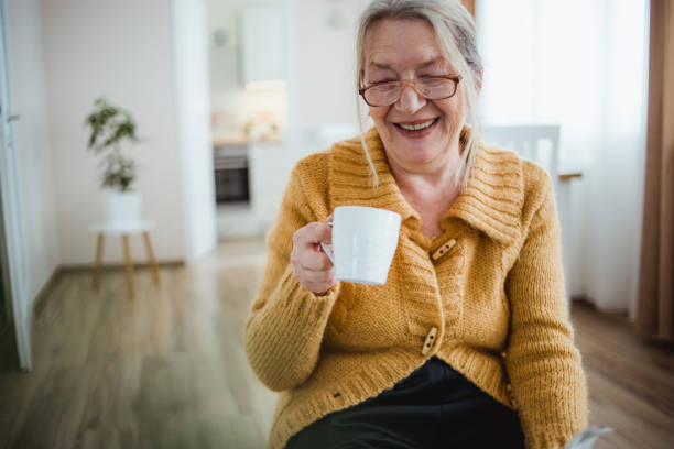 istock An elderly woman reading a newspaper at home and drinking coffee 1214916149