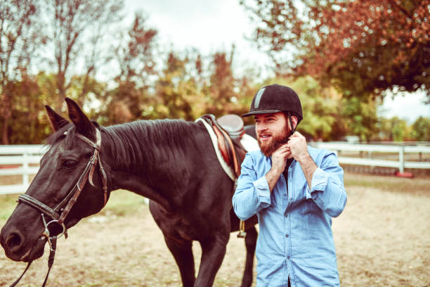 istock Handsome Male Putting On Helmet Before Riding Horse 1214917049