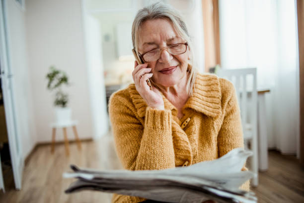 istock An elderly woman reading a newspaper at home and drinking coffee 1214917135