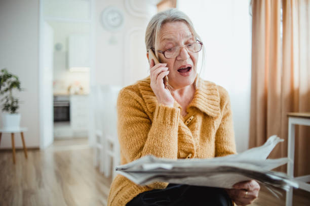 istock An elderly woman reading a newspaper at home and drinking coffee 1214917315