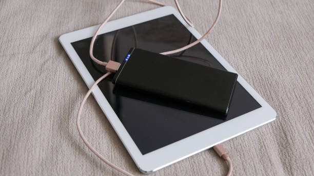Close up shot of male hand plugging in charger into digital tablet