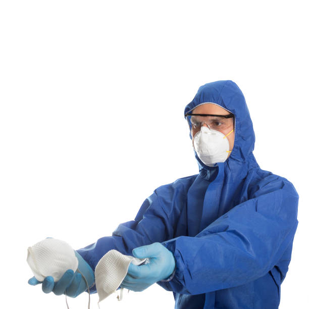 istock Man in protective clothing with face masks in hands 1214918915