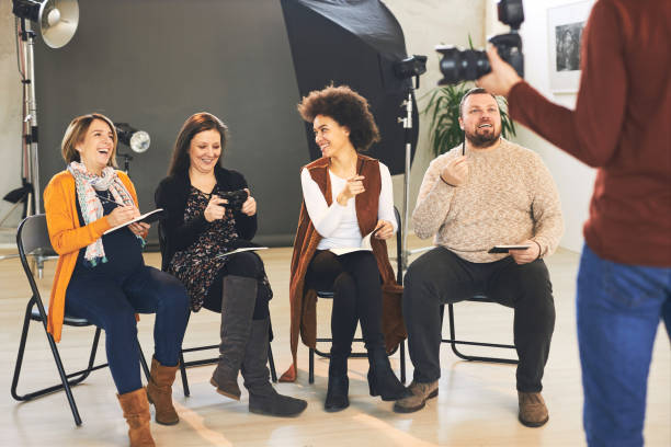 istock Group of happy attendees sitting and listening their tutor who holding camera and explaining them basics. 1214919140