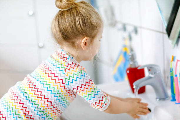 carina bambina che si lava le mani con acqua e sapone in bagno. adorabile bambino che impara a pulire le parti del corpo. azione di routine igienica durante la malattia virale. bambino a casa o all'asilo nido. - home interior sparse bedroom inside of foto e immagini stock