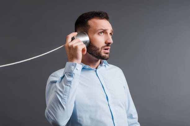 istock bearded man holding tin can near ear while listening isolated on grey 1214920346