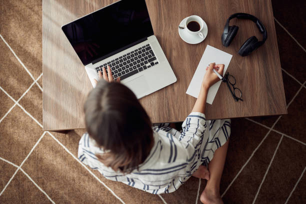 istock Working home concept -Woman using a laptop computer for work at home top view 1214921263