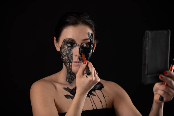 istock woman putting makeup on for evening event. Halloween. Creative face paint 1214924819
