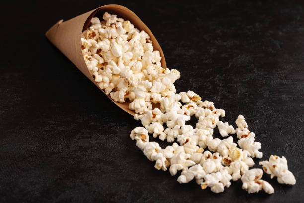 istock Popcorn in paper cone on black background. Flat lay. Top view. Copy space 1214924969