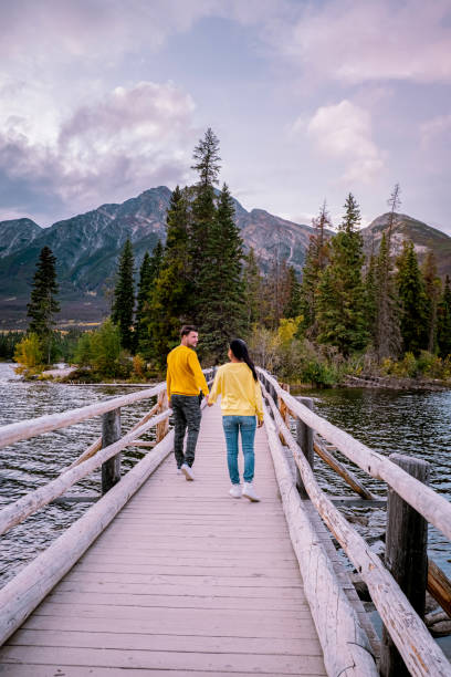 istock couple by the lake watching sunset, Pyramid lake Jasper during autumn in Alberta Canada, fall colors by the lake during sunset, Pyramid Island Jasper 1214925877