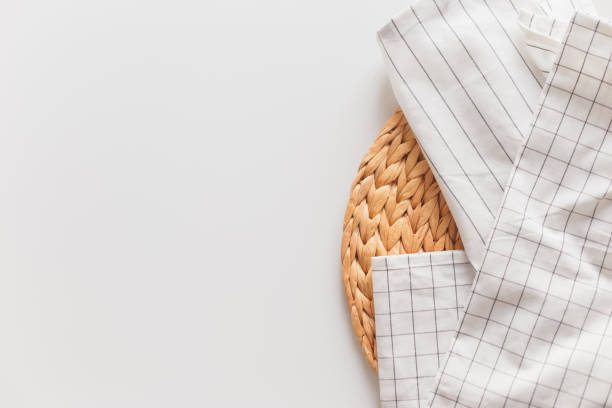 istock White striped and checkered tablecloth and wicker placemat close-up, isolated on white with copy space. 1214926131